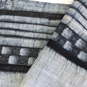 May include: A close-up of a blue and white fabric with a black stripe pattern. The fabric has a textured, woven look and is folded in half.
