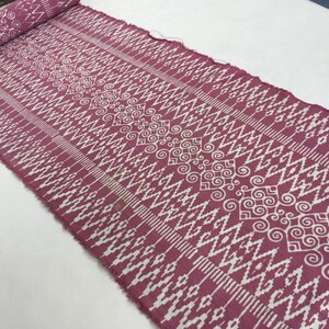 Könnte beinhalten: Ein rosa Stoff mit einem weißen geometrischen Muster. Das Muster zeigt ein sich wiederholendes Design aus Spiralen und Zickzacklinien.