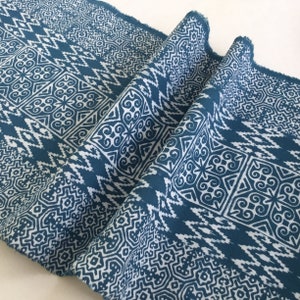 Könnte beinhalten: Türkiser Stoff mit einem weißen geometrischen Muster. Das Muster zeigt sich in sich wiederholenden Quadraten mit komplizierten Designs.