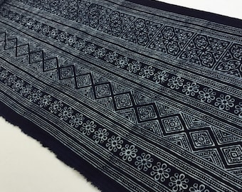 May include: Dark navy blue fabric with a repeating white pattern. The design includes floral, diamond, and geometric shapes arranged in horizontal stripes. The fabric is likely used for sewing or crafting projects.