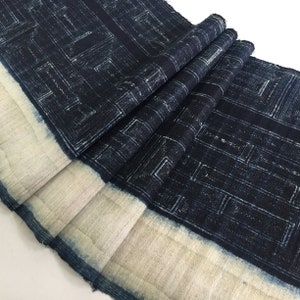 May include: A dark blue indigo fabric with a white geometric pattern. The fabric has a white border and is folded in several places.