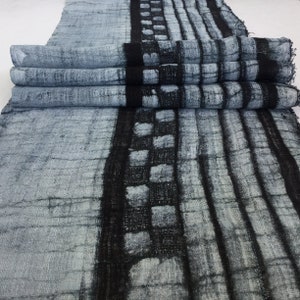 May include: A close-up of a gray and black fabric with a repeating pattern of squares and lines. The fabric is folded in thirds, showing the pattern on both sides.