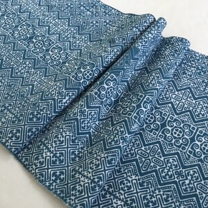 Könnte beinhalten: Ein gefaltetes Stück Stoff mit einem blauen und weißen geometrischen Muster. Der Stoff hat eine gewebte Textur und einen leicht verblassten Look.