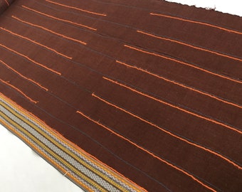 Peut inclure: Un tissu brun avec des rayures orange. Le tissu a une bordure décorative avec des rayures jaunes, orange et brunes.