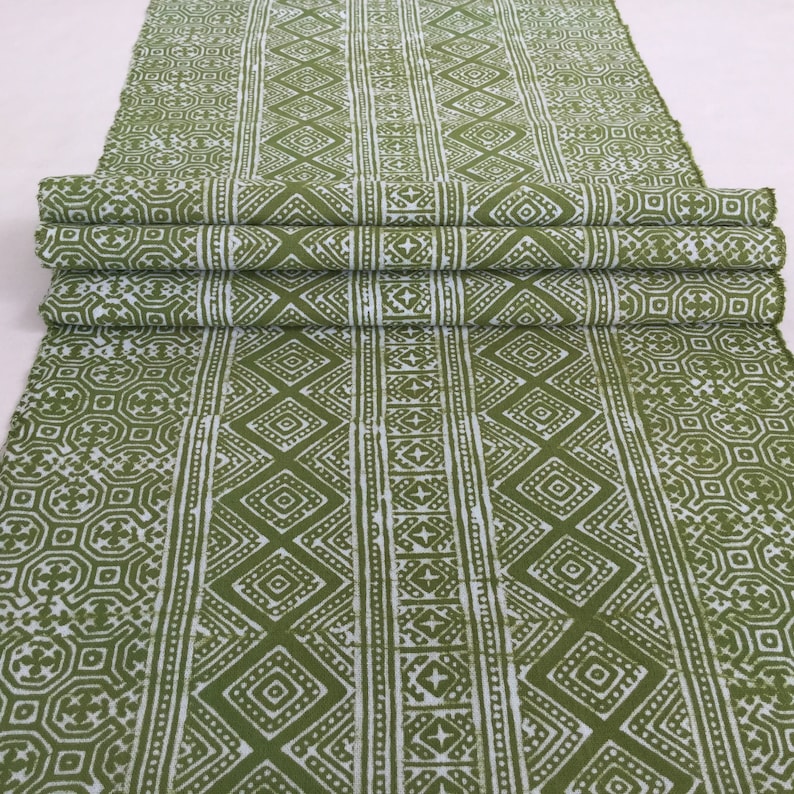 Pu&ograve; includere: Tessuto verde e bianco con un motivo geometrico. Il tessuto &egrave; piegato in tre parti e ha uno sfondo bianco con un motivo geometrico verde.