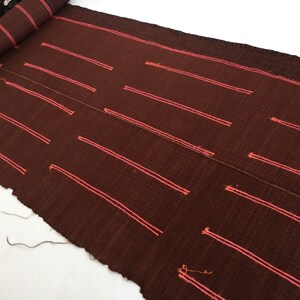 May include: A brown fabric with pink stripes woven into the fabric. The fabric is rolled up at the top.