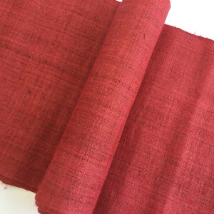 May include: A roll of red burlap fabric. The fabric has a rough texture and is perfect for crafting projects.