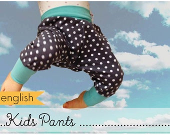 Puede incluir: Un pantalón para niños de lunares negros y blancos con puños azul turquesa. El pantalón está colgado en el aire contra un cielo azul con nubes blancas. El texto "english Kids Pants" está en la parte inferior de la imagen.