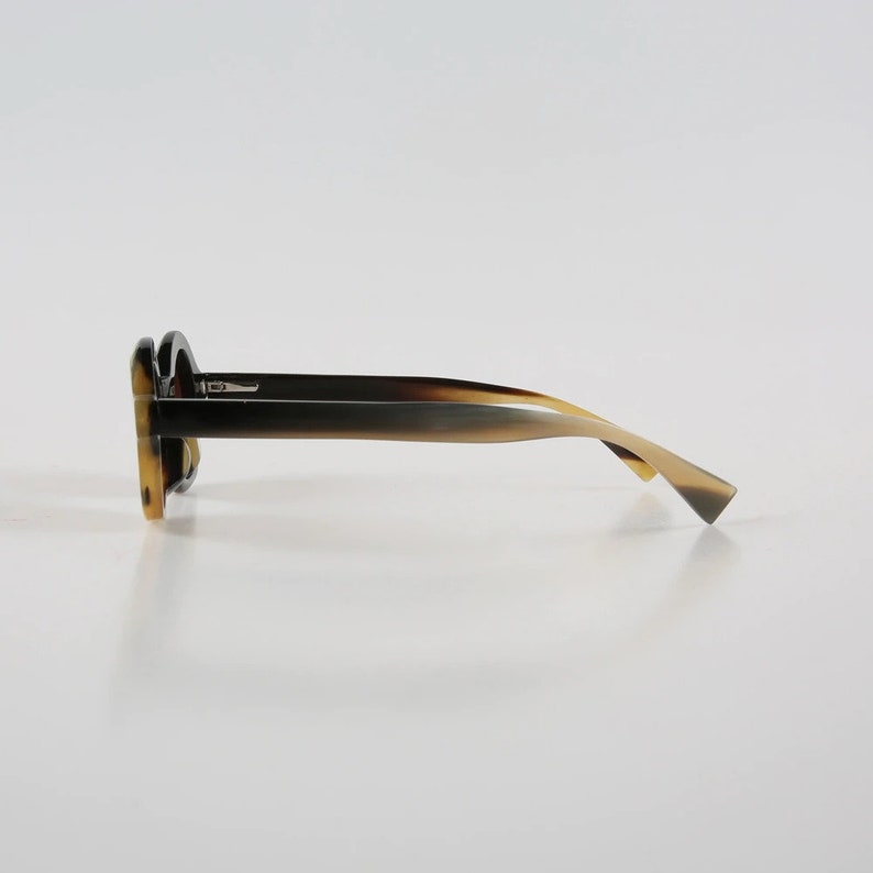 May include: A pair of tortoiseshell sunglasses with a dark brown frame and light brown temples.