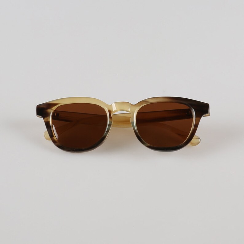 May include: Brown and beige tortoiseshell sunglasses with brown lenses.
