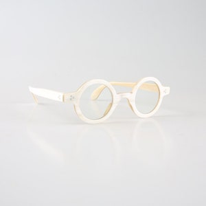K&ouml;nnte beinhalten: Wei&szlig;e runde Brille mit cremefarbenem Rahmen. Die Brille hat ein schlichtes Design und ist aus leichtem Material gefertigt.