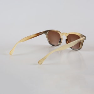 May include: A pair of brown and beige tortoiseshell sunglasses with brown lenses. The sunglasses have a classic, retro style.