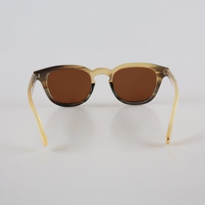 May include: Brown tortoiseshell sunglasses with brown lenses. The sunglasses have a classic, rounded shape and are made from a durable material.