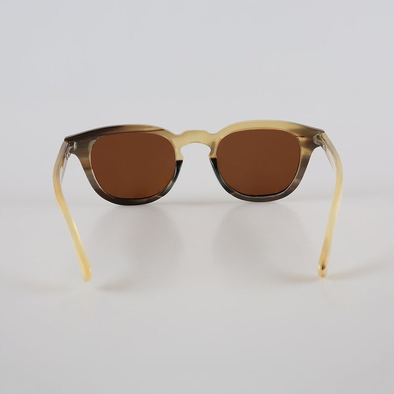 May include: Brown tortoiseshell sunglasses with brown lenses. The sunglasses have a classic, rounded shape and are made from a durable material.