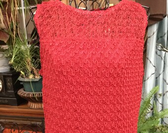 May include: A red sleeveless crochet top with a delicate pattern. The top has a round neckline and a loose fit.