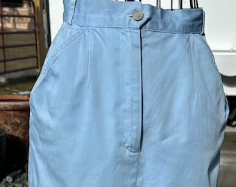 May include: A light blue skirt with a button closure and pockets. The skirt is made of a solid-colored fabric and has a classic, tailored design. The skirt is displayed on a mannequin.