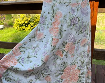 May include: A white skirt with a floral print featuring pink and purple flowers. The skirt is made of a lightweight fabric and has a flowy silhouette.