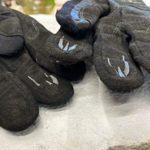 以下が含まれることがあります： グレーのアクセントが付いた黒い革の手袋のペア。手袋は質感のある表面を持ち、屋外での活動のために設計されています。
