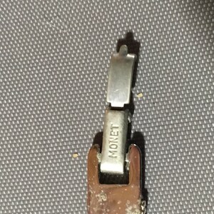 May include: A silver metal watch band with a clasp that says "MONET" on it.