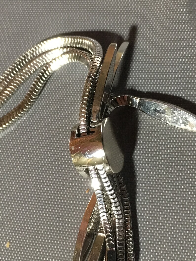 May include: A silver chain necklace with a clasp that is made of multiple interwoven strands.