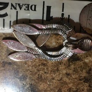 May include: Silver tone dangle earrings with a chain link design and multiple leaf-shaped accents.