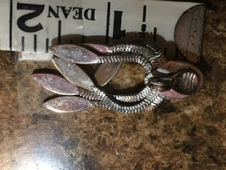May include: Silver tone dangle earrings with a chain link design and multiple leaf-shaped accents.