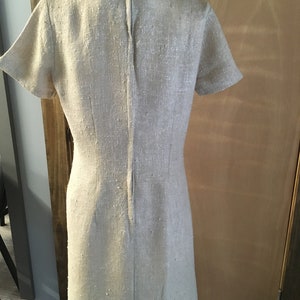 Puede incluir: Un vestido de lino beige con mangas cortas y una cremallera en la espalda.