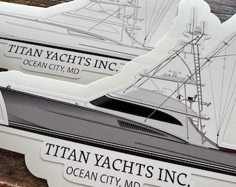 May include: Two stickers featuring a detailed illustration of a yacht. The yacht is primarily gray with black accents and intricate rigging details. The text "TITAN YACHTS INC. OCEAN CITY, MD" is printed on each sticker.