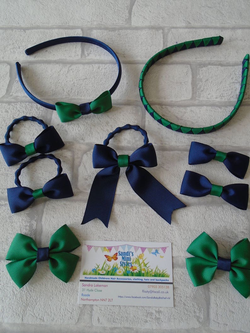 May include: A collection of children's hair accessories, including headbands and bows. The items feature a color scheme of navy blue and green. The business card in the image reads "Sandi's Mini Styles".