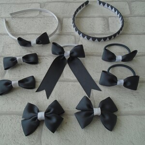 May include: A collection of dark gray and white hair accessories, including headbands, hair ties, and bow clips. The headbands feature a solid white band with a bow and a black and white geometric pattern. The bows have a white center.