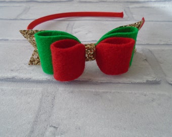 Puede incluir: Una diadema festiva con una banda de plástico roja y un lazo de fieltro. El lazo tiene un centro de purpurina dorada, bucles de fieltro verde y bucles de fieltro rojo. Este accesorio es temático de Navidad.