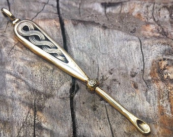 May include: A gold-colored metal spoon with a Celtic knot design on the handle. The spoon has a rounded end and is about 6 inches long.