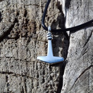 Op de afbeelding: Een zilveren Mjolnir-hangerketting aan een zwart leren koord. De hanger is een replica van Thors hamer uit de Noorse mythologie.