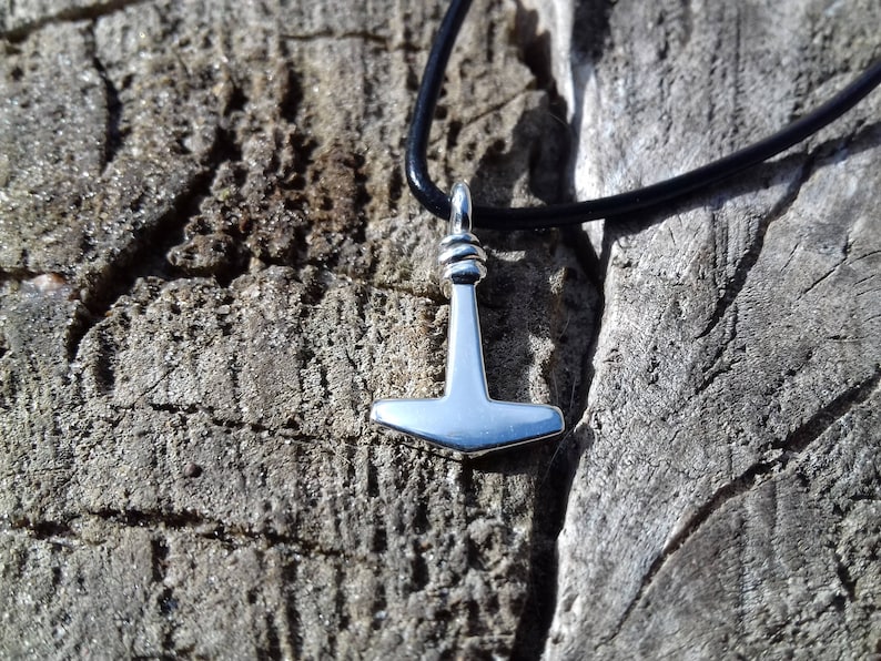 Op de afbeelding: Een zilveren Mjolnir-hangerketting aan een zwart leren koord. De hanger is een replica van Thors hamer uit de Noorse mythologie.