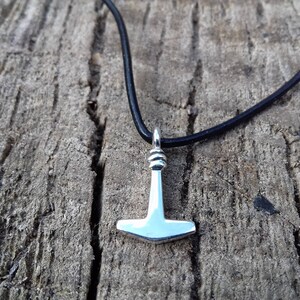Op de afbeelding: Een zilveren Mjolnir-hangerketting aan een zwart leren koord. De hanger is een replica van Thors hamer uit de Noorse mythologie.