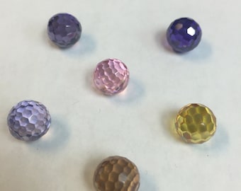 Puede incluir: Seis cuentas de vidrio facetadas en varios colores, incluyendo morado, rosa, amarillo y marrón.