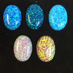 May include: Six oval-shaped opals with different color patterns. The opals are arranged in two rows of three. The opals are a light blue, a dark blue with green flecks, a light blue with white flecks, a light pink with white flecks, a light yellow with pink flecks, and a light yellow with white flecks.