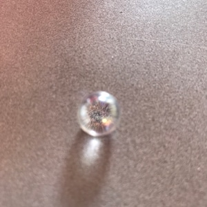 Puede incluir: Una canica de vidrio transparente con un acabado brillante e iridiscente.