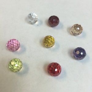 Puede incluir: Ocho cuentas de vidrio facetadas en varios colores, incluyendo transparente, rosa, rojo, amarillo, verde, marr&oacute;n y morado.