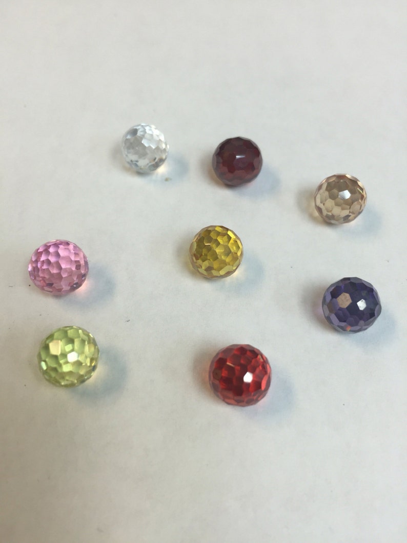 Puede incluir: Ocho cuentas de vidrio facetadas en varios colores, incluyendo transparente, rosa, rojo, amarillo, verde, marr&oacute;n y morado.