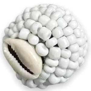 May include: White bead ball with a cowrie shell embedded in the side. The ball is made of small, round beads that are tightly packed together.