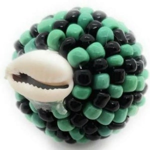 May include: A green and black beaded sphere with a white cowrie shell attached. The beads are small and tightly packed, creating a textured surface.