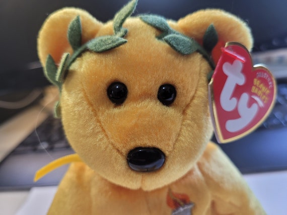 Ty Beanie Babies Victory Gold Bear With Torch On Chest, Fig Leaf Crown And Yellow Ribbon Around Neck (Internet Exclusive)