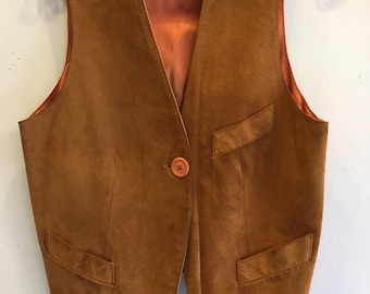 May include: A brown suede vest with a single button closure and two pockets on the front. The vest has a contrasting orange lining and a label that reads "Henry Rothdel" and "M".