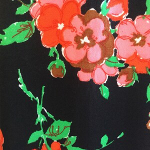 May include: Black fabric with a floral pattern featuring pink, red, and green flowers. The flowers are stylized and have a retro look.