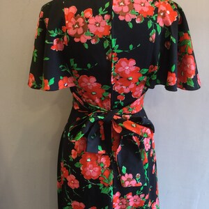 May include: A black maxi dress with a floral print in shades of pink, red, and green. The dress has a wrap style bodice and a tie at the waist.