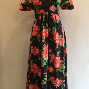 May include: A long black maxi dress with a floral print featuring pink and green flowers. The dress has a v-neckline and short sleeves.