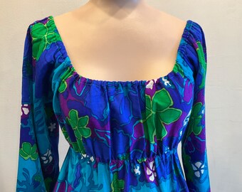 May include: A vintage, long-sleeved dress with a square neckline. The dress features a vibrant floral pattern in shades of blue, green, purple, and white. The fabric is gathered at the neckline and waist, creating a flowing silhouette.