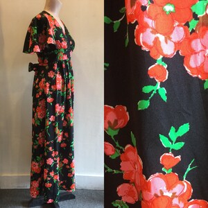 May include: A long black maxi dress with a V-neckline and short sleeves. The dress has a floral print with pink, red, and green flowers.