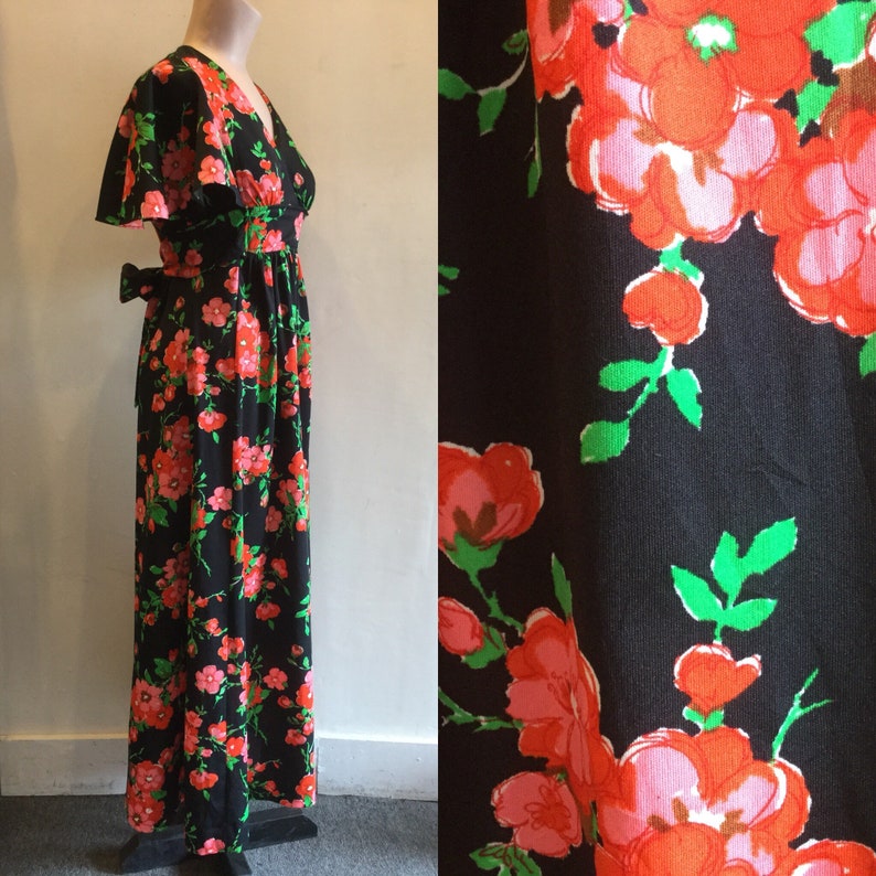 May include: A long black maxi dress with a V-neckline and short sleeves. The dress has a floral print with pink, red, and green flowers.